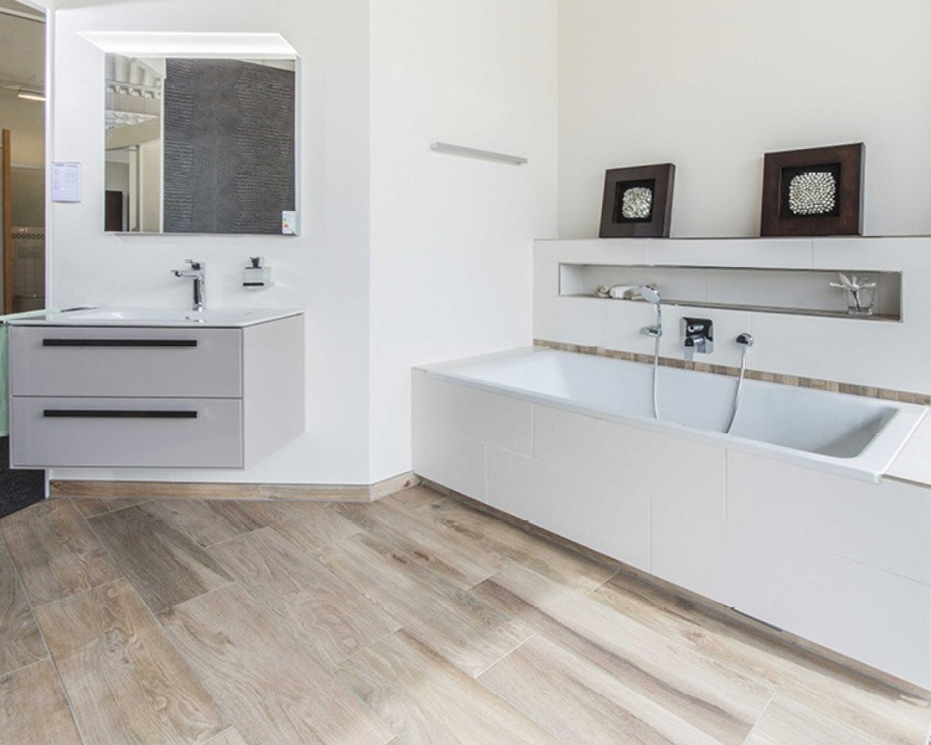 Helles Badezimmer mit Eckwaschtisch und Badewanne mit Ablage.