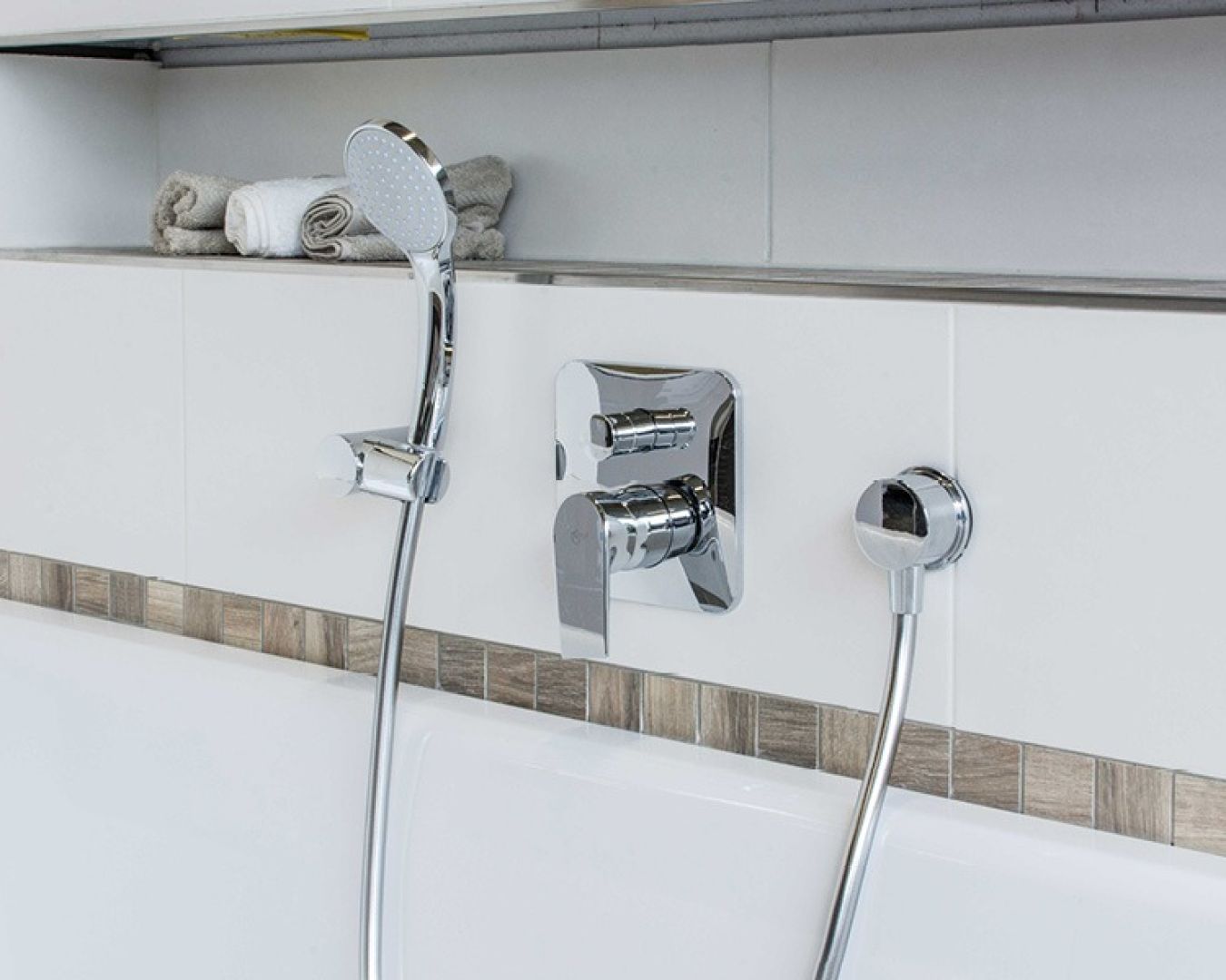 Moderne Badewannenarmatur mit Handbrause und integrierter Ablagefläche.